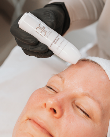 Person receiving a skin treatment by a gloved hand.
